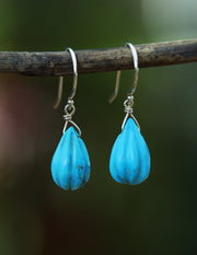 an ear wire that features carved natural, turquoise on sterling silver shepherd hooks.  The length is approximately 1.25." 