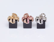 3 colors of 14kt gold ribbon: white set with black diamonds, rose set with rose diamonds, and yellow set with Champagne diamonds.  Sixteen diamonds (approx .11 cts ) sparkle on each charm.  The gift box is a black spinel cube.