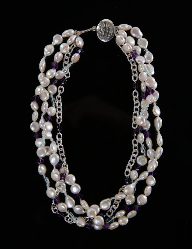 Sterling silver.  Gems: white freshwater pearls, amethyst, and aquamarine.  White Orchid Studio logo clasp.   Four-strand torsade.  Approximate length is 18.”