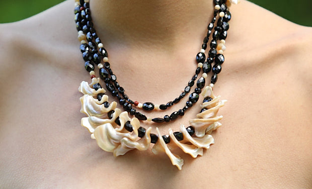 Sterling silver.  Gems:  black spinel, mother of pearl fringe, and red jasper.  3 strand bib necklace.  White Orchid Studio’s vanilla bean clasp.  The longest strand is 20.”