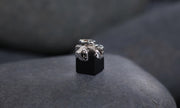 14kt white gold ribbon, set with 16 black diamonds (approx .11 cts) on a black spinel cube.