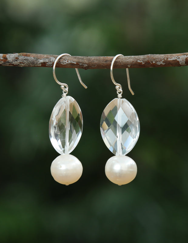 A drop ear wire of beautiful, white freshwater pearls, paired with a faceted, pear shape crystal quartz. A sterling ear wire suspends the gems for an approximate 2" length.