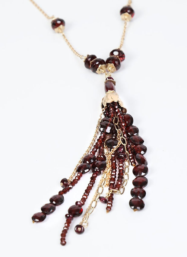 14kt. yellow gold.  A 35" necklace of gold chain and almandine garnet. The necklace ends in a 4” many-strand tassel. 