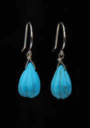 an ear wire that features carved natural, turquoise on sterling silver shepherd hooks.  The length is approximately 1.25." 